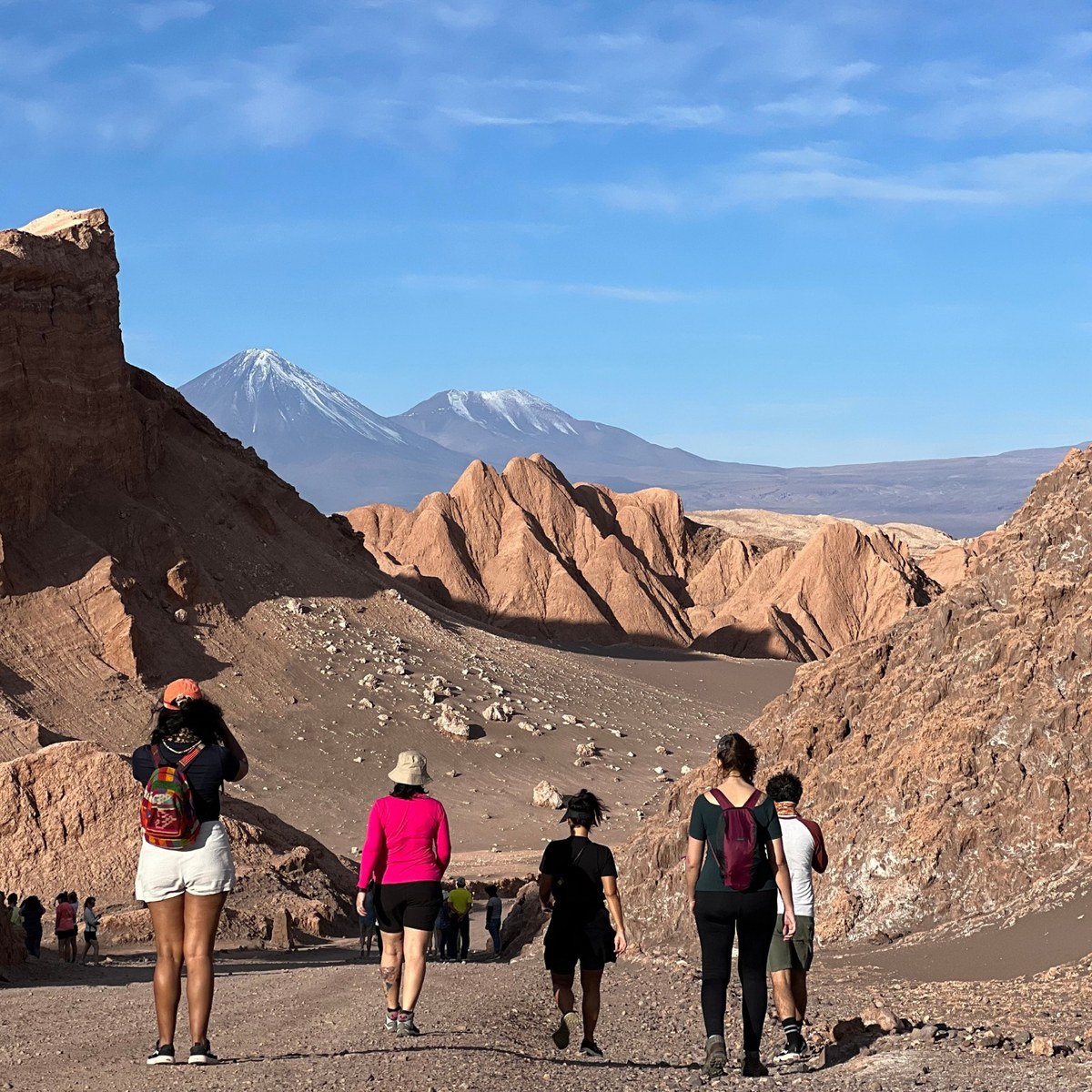 Grupo caminhando no Valle de la Luna com o vulcão Licancabur ao fundo, Deserto do Atacama